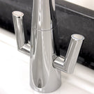 Silver bridge style kitchen faucet with two handles.