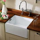 White apron-front kitchen sink with a chrome bridge style faucet.