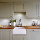 White apron-front sink with a silver bridge faucet.