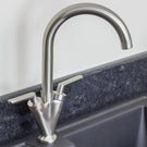 Modern chrome curved kitchen mixer tap on black countertop
