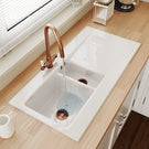 White kitchen sink with bronze faucet on countertop.