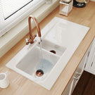 White kitchen sink with bronze faucet on countertop.