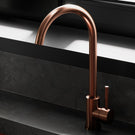 Copper kitchen faucet on black countertop.