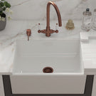 White ceramic sink with a copper-toned faucet.