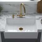 Classic white apron-front ceramic sink with gold faucet