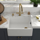 White ceramic sink with a gold bridge faucet