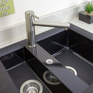 Black kitchen sink with silver faucet and drain in a modern kitchen setting.