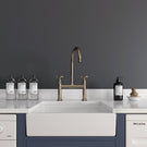 White ceramic farmhouse sink with gold waste