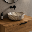 Marble-patterned sink on a wooden vanity with black faucet and soap dispenser.