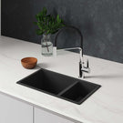 Black kitchen sink with faucet on a white countertop against a dark gray wall.
