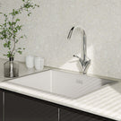Modern kitchen sink with faucet and decorative elements on a light countertop.
