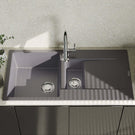 Gray kitchen sink with faucet on a countertop with a light gray wall in the background