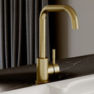 Gold kitchen faucet on a marble countertop with a neutral background