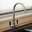 Stainless steel kitchen faucet near window.