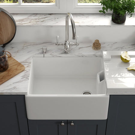 White farmhouse sink with a tall, modern, silver faucet.