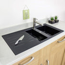 Black kitchen sink with a knife on a countertop, wooden cabinets, and a motivational sign in the background.