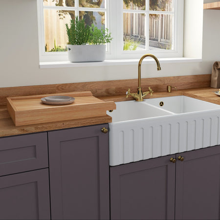 Modern kitchen with a white farmhouse sink, wooden countertops, and purple cabinets.