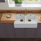 White kitchen sink with gold faucet in a modern kitchen setting