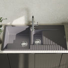 Gray kitchen sink with faucet on a countertop with a light gray wall in the background