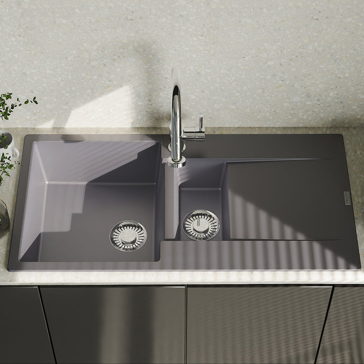 Gray kitchen sink with faucet on a countertop with a light gray wall in the background
