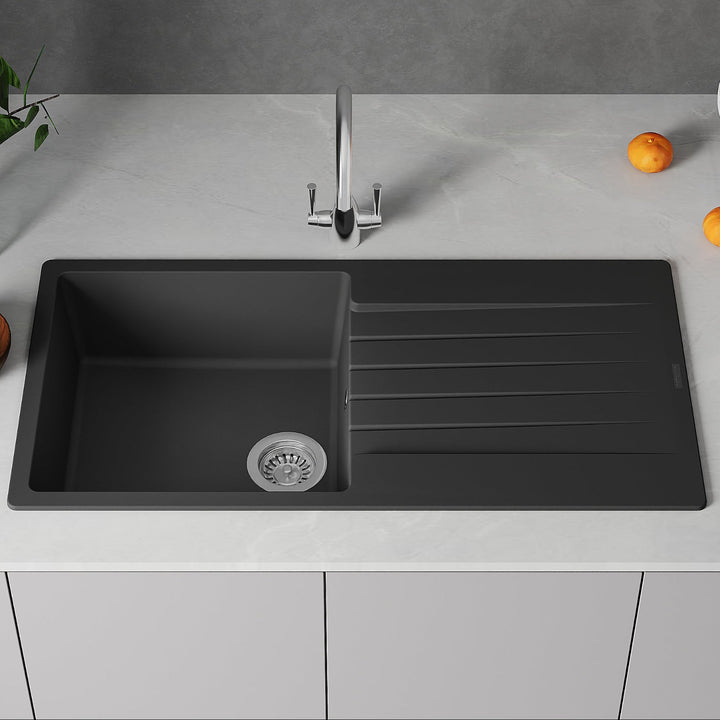 Black kitchen sink with faucet on a gray countertop