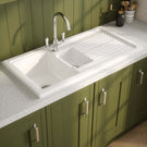 Green kitchen cabinets with a white sink and countertop.
