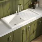 Kitchen sink with green cabinets and a window in the background
