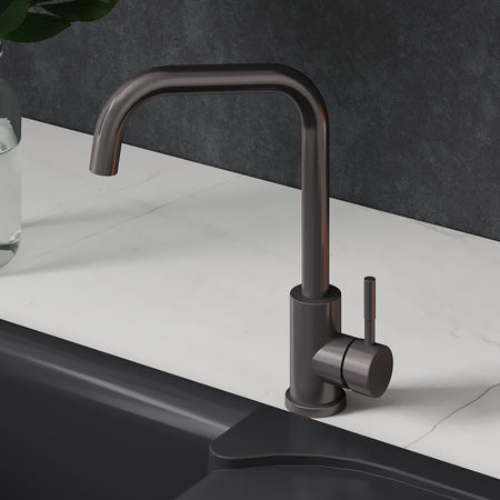 Black kitchen faucet on a white countertop with oranges and a plant.