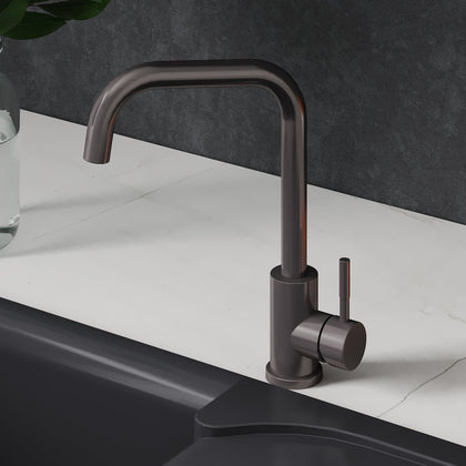 Black kitchen faucet on a white countertop with oranges and a plant.