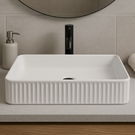 White rectangular sink on a bathroom counter with a towel and soap dispenser.